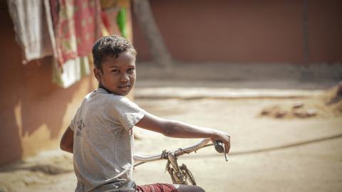 Smiling Boy Riding a Bicycle on a Village Path